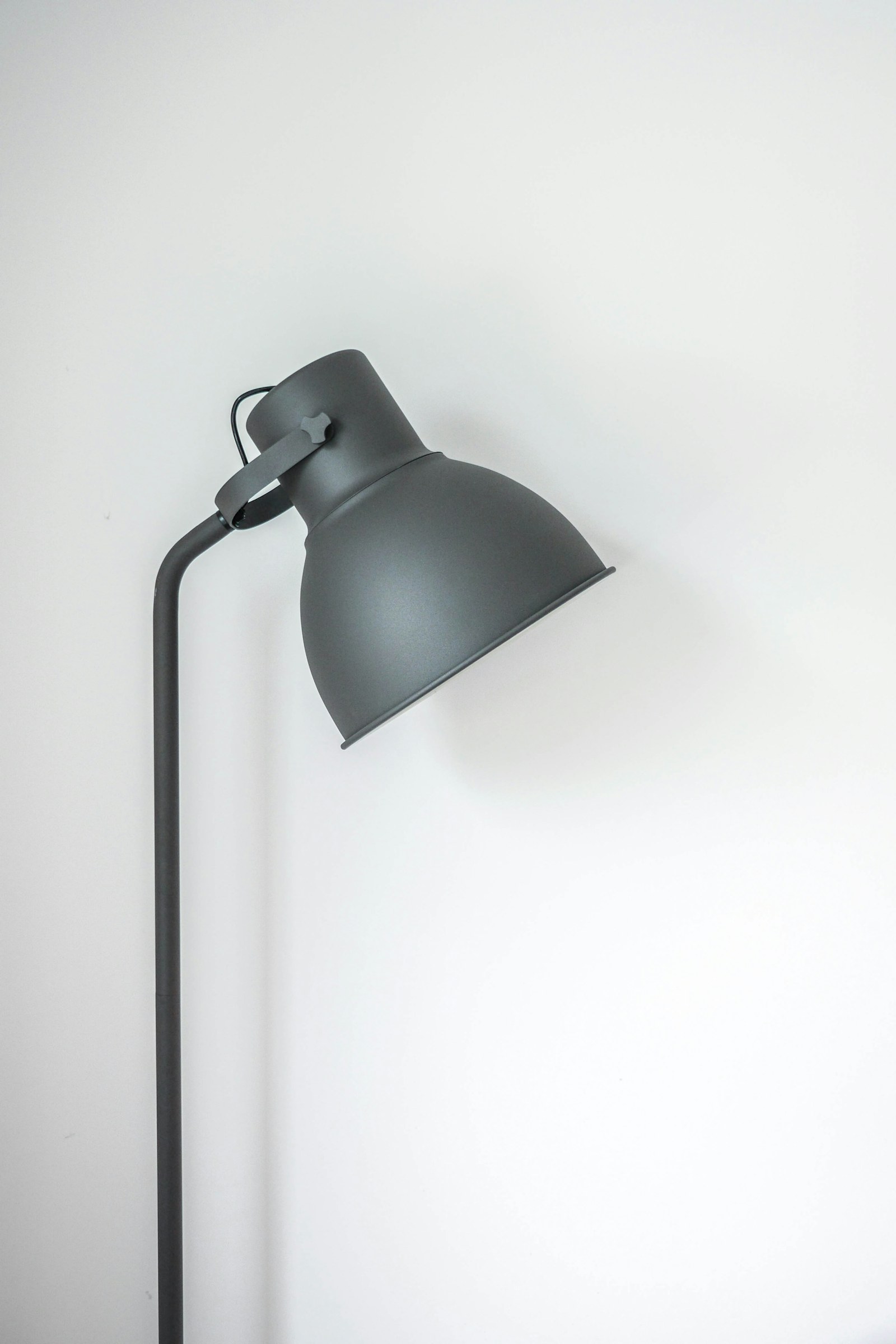 Adjustable desk lamp lighting a notebook and laptop in the evening.